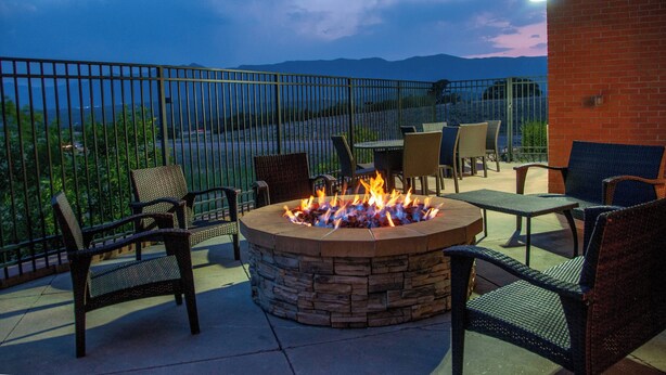 A fire pit surrounded by wicker chairs and tables, with a view of mountains in the background. - Fairfield Inn & Suites Colorado Springs N./Air Force Academy (Colorado Springs)