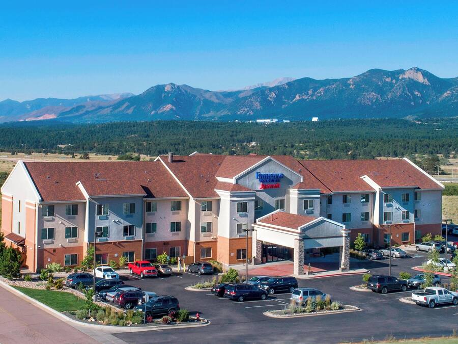 A multi-story hotel with a parking lot, surrounded by mountains.
