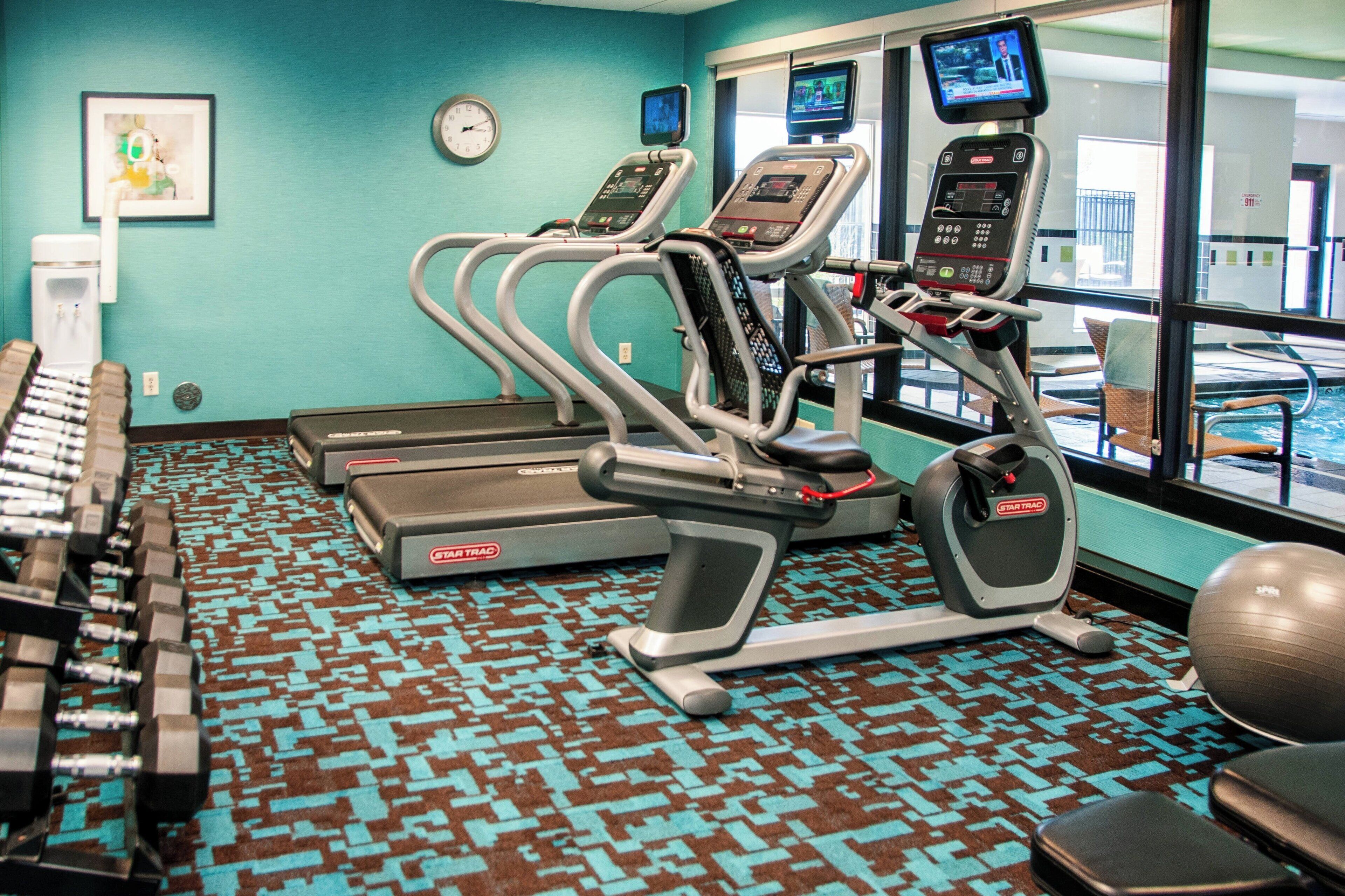 Un gimnasio con cintas de correr, mancuernas y pelotas de ejercicio.