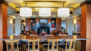 A hotel lobby with a large wooden reception desk, multiple seating areas, and a fireplace. - Fairfield Inn & Suites Colorado Springs N./Air Force Academy (Colorado Springs)