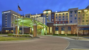 A multi-story hotel with a prominent entrance, a covered walkway, and a flagpole with the American flag. - Embassy Suites Columbus-Airport (Columbus)