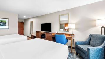 A hotel room with two beds, a desk, a chair, a television, a mirror, and a lamp.