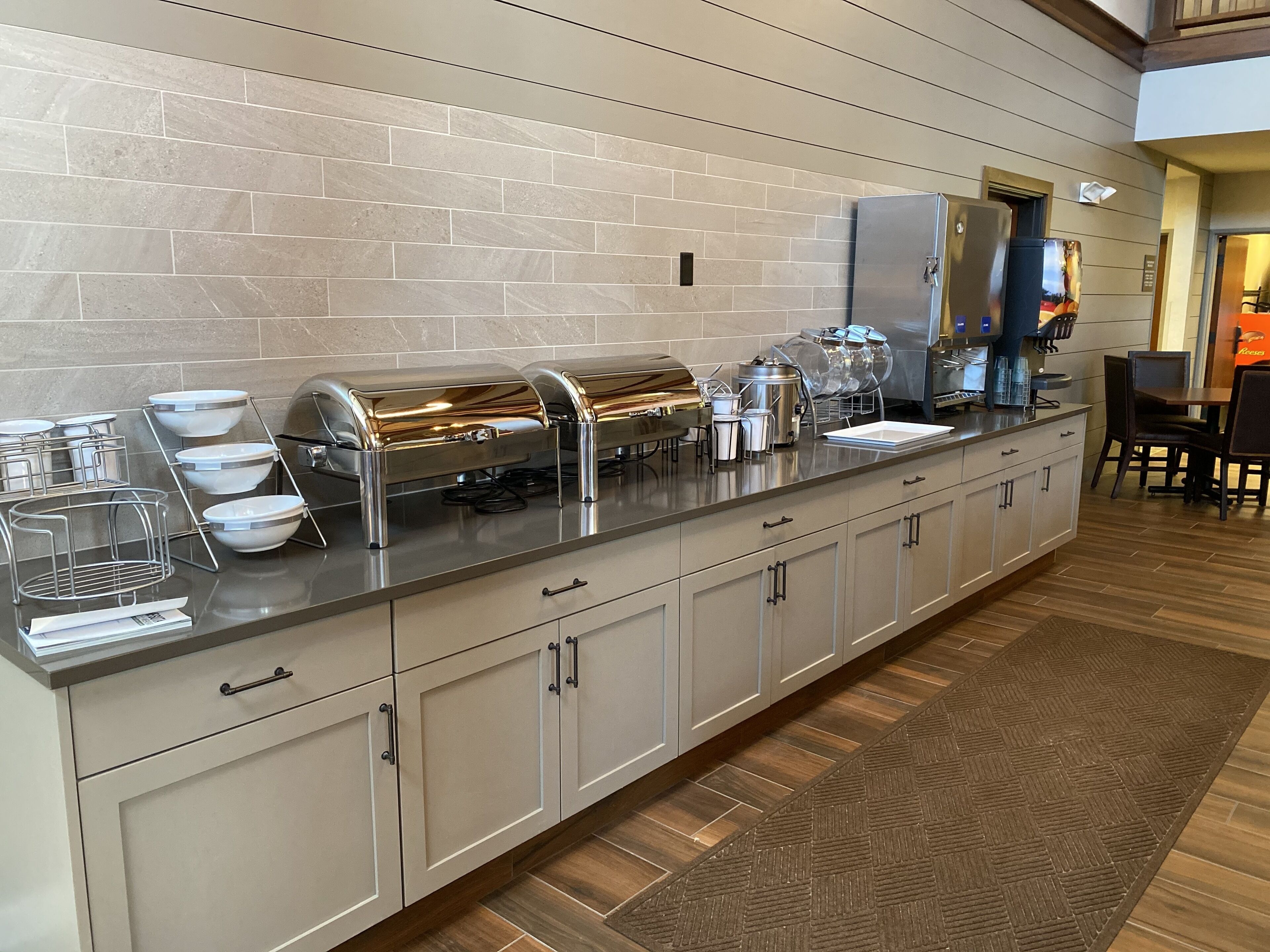 A buffet setup with stainless steel appliances, a tiled backsplash, and a wooden floor.