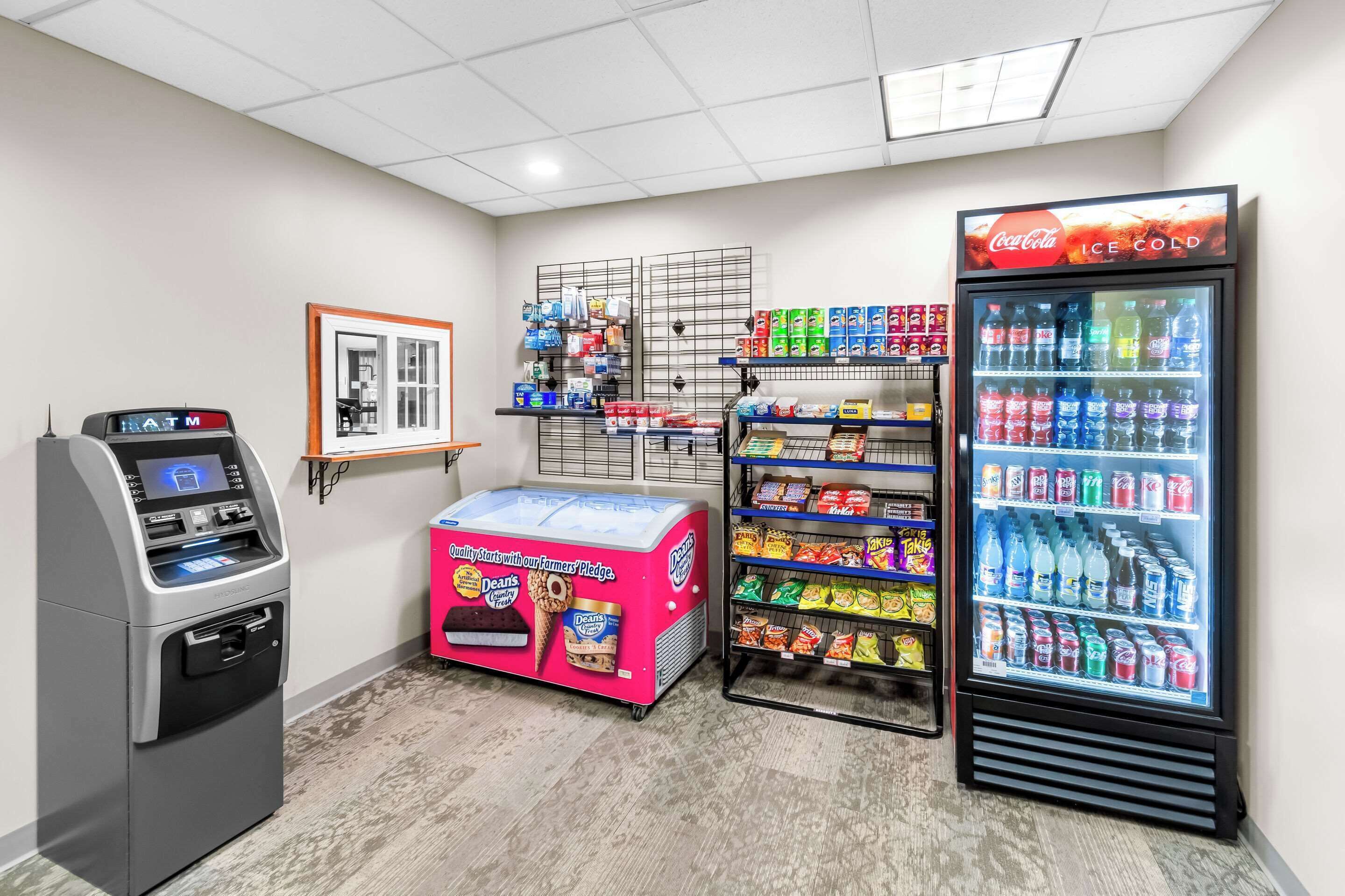 Un quiosco de autoservicio, un mostrador refrigerado y un refrigerador Coca-Cola en un establecimiento comercial.
