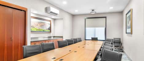 Une salle de conférence avec une longue table en bois, des chaises noires et une grande fenêtre.