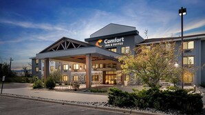 A Comfort Inn & Suites hotel with a covered entrance, stone facade, and landscaped surroundings.
