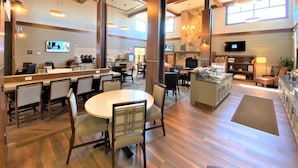 A spacious hotel lobby with a central dining area, a bar, and a fireplace.