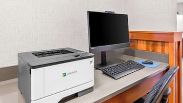 A Lexmark printer and monitor on a desk with a keyboard and mouse, against a textured wall.