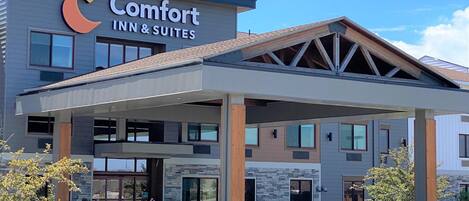 A Comfort Inn & Suites hotel with a modern design, featuring a covered entrance and a stone facade.