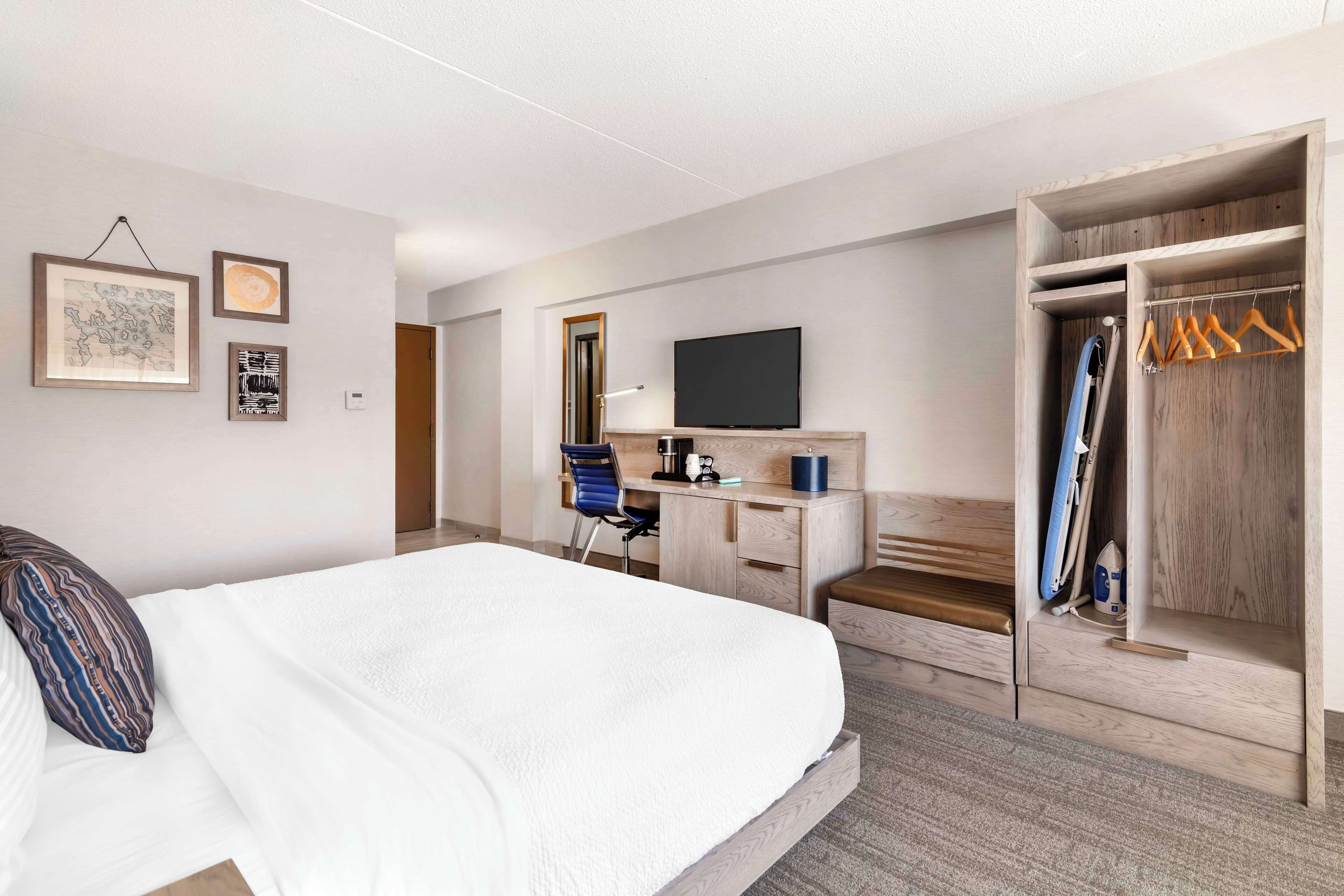 A hotel room with a bed, a desk, a TV, a wardrobe, and a mirror.