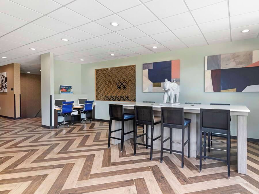 Um lobby moderno de hotel com piso em padrão herringbone, balcão de recepção, área de bar e assentos.