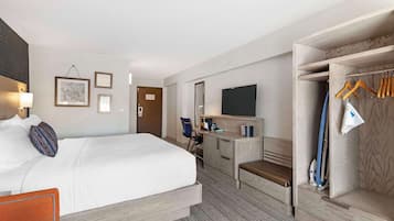 Une chambre d’hôtel équipée d’un lit, d’un bureau, d’une télévision et d’un placard avec des cintres.