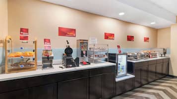 Una barra de desayuno con diferentes alimentos, una máquina de café y una vitrina.