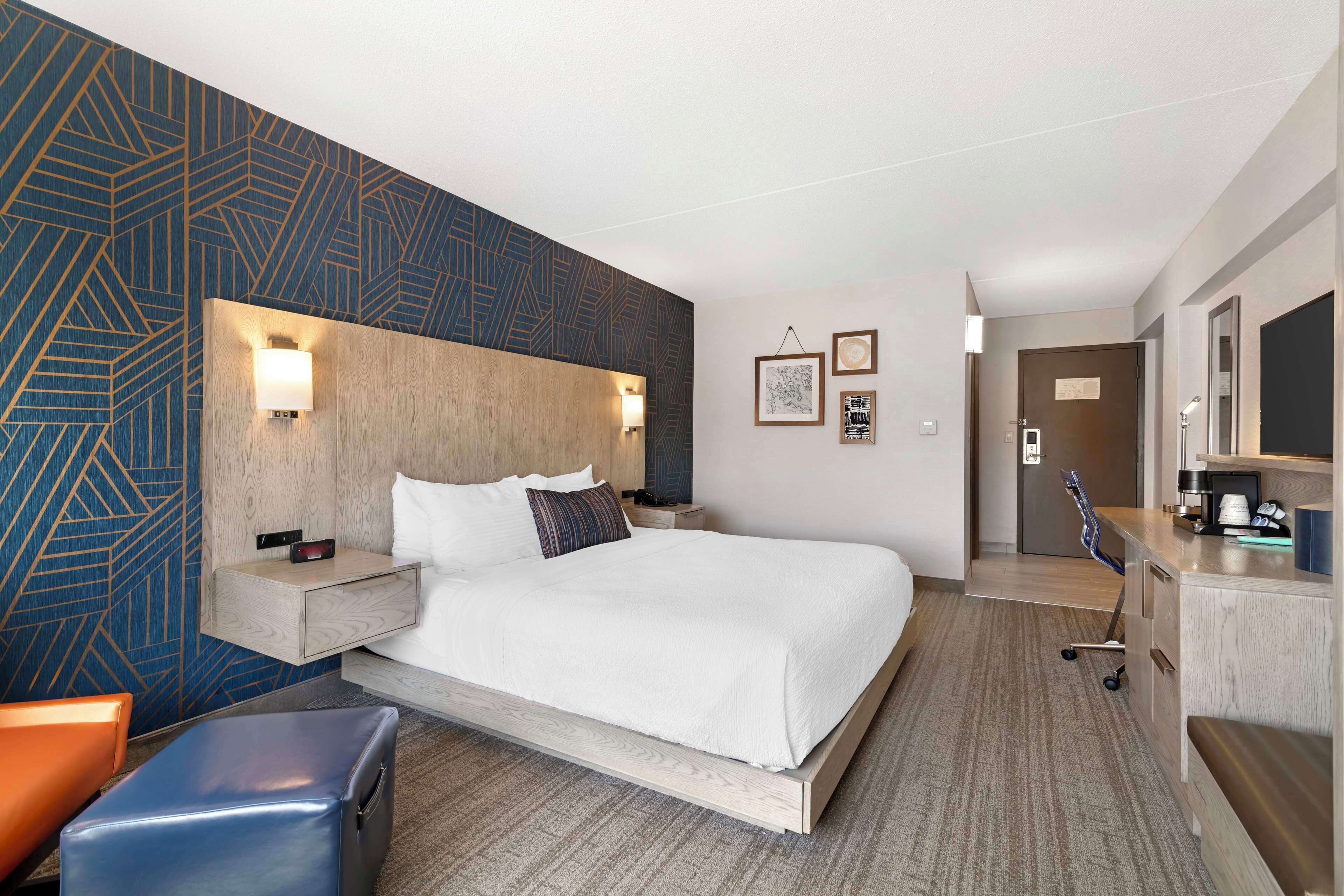 A hotel room with a large bed, bedside tables, a desk, and a chair.