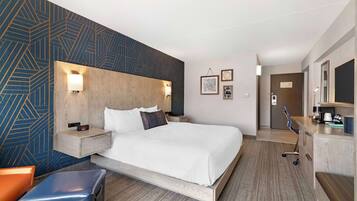 A hotel room with a large bed, bedside tables, a desk, and a chair.