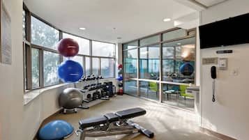 A gym with exercise equipment, a bench, and large windows.