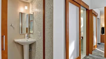 Un bagno moderno con uno specchio grande, un lavandino e una parete rivestita in piastrelle.