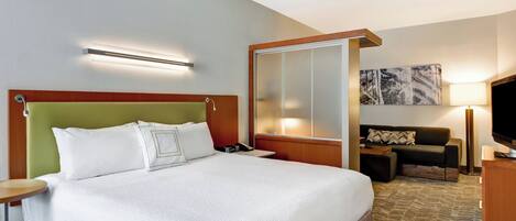 Una habitación de hotel con una cama grande, un escritorio, una silla, un televisor y un cuadro en la pared.