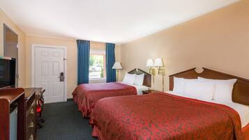 Habitación de hotel con dos camas, televisor, escritorio y ventana con cortinas.