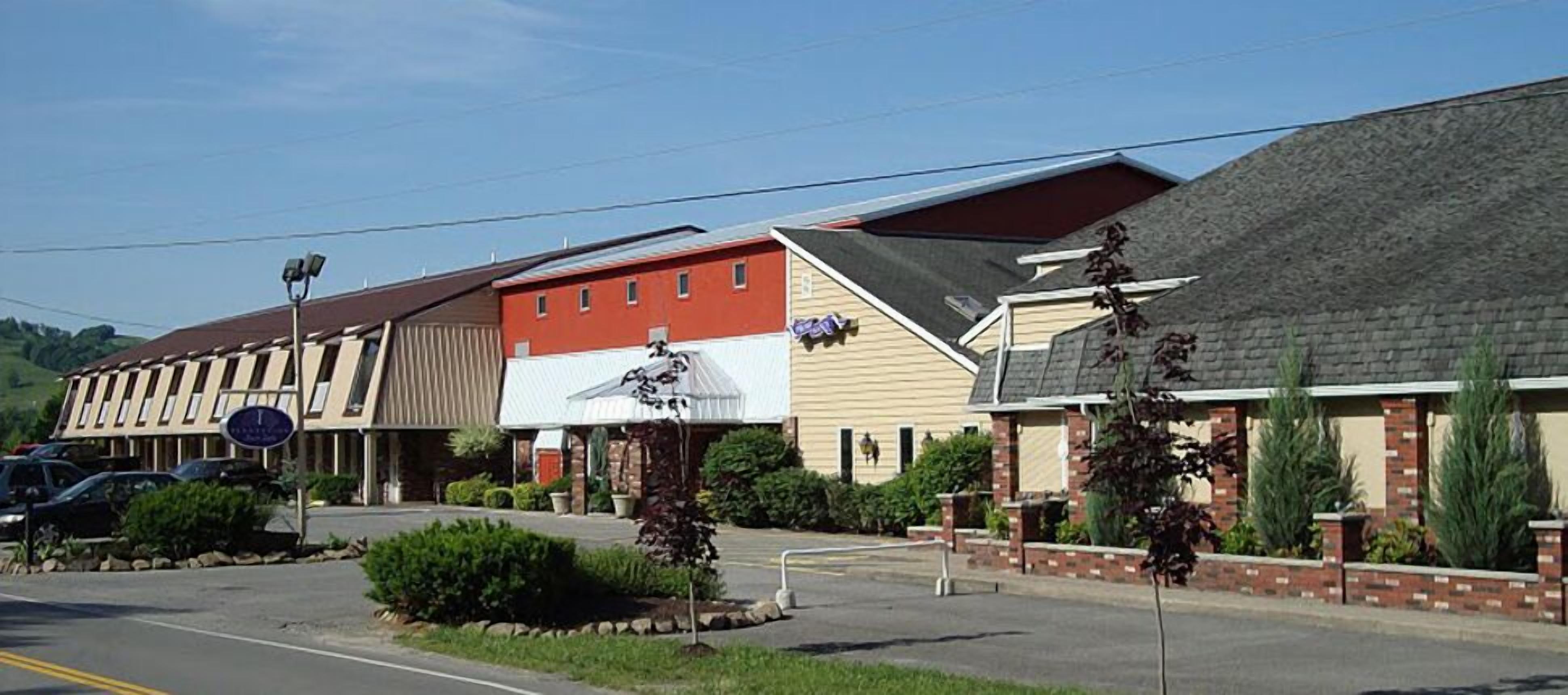 A motel with a row of rooms, a parking lot, and a clear sky.