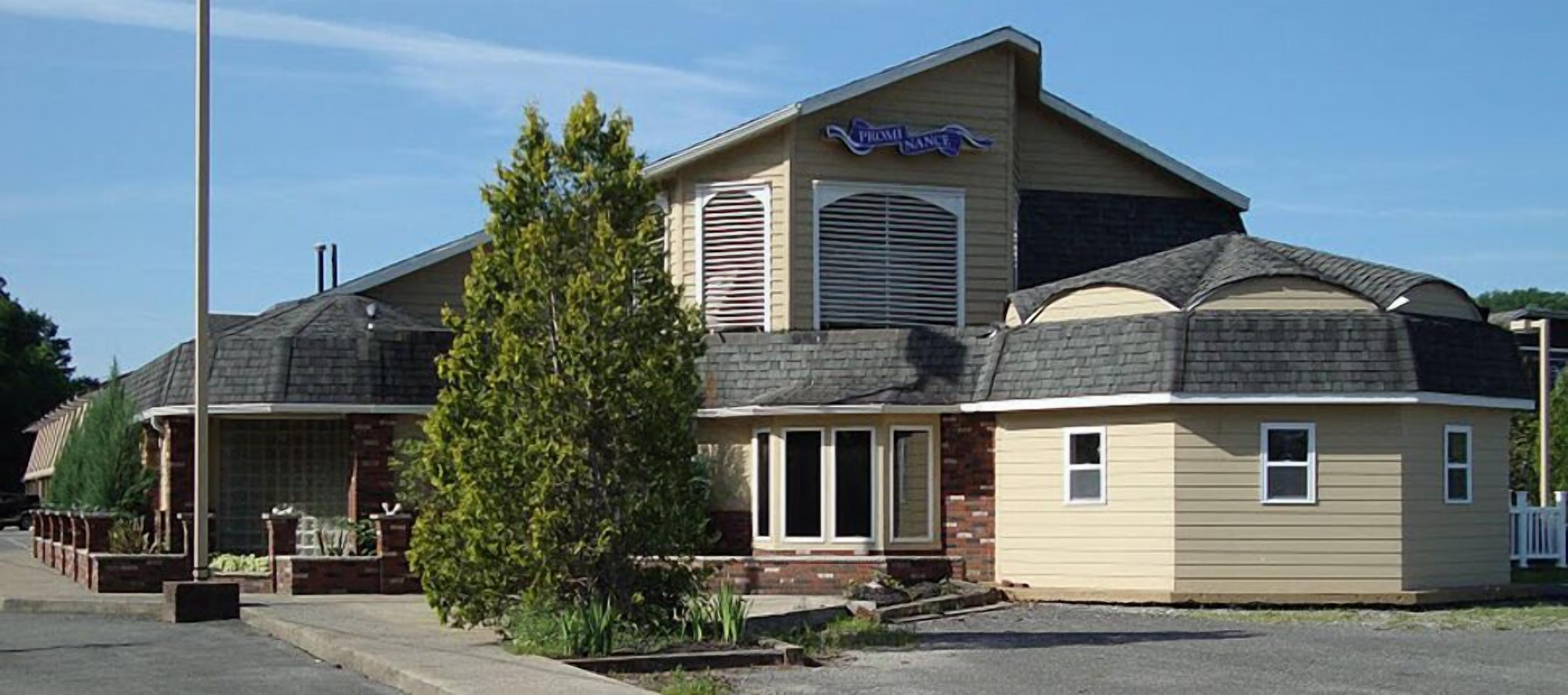 A two-story building with a 'Prominence' sign, a brick facade, and a large tree in front.