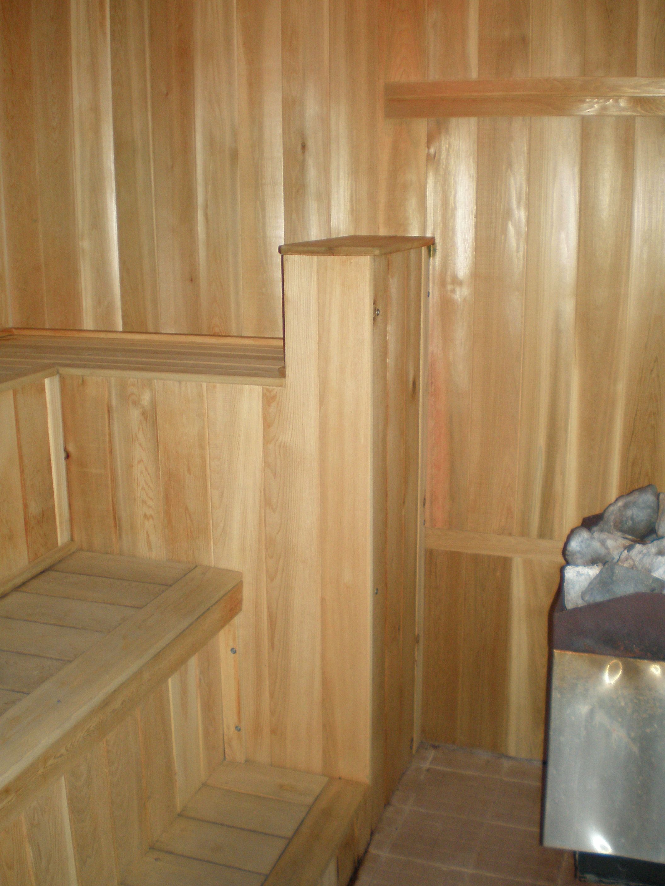 Un sauna de madera con bancos y un banco de piedra.