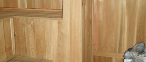 Un sauna de madera con bancos y un banco de piedra.