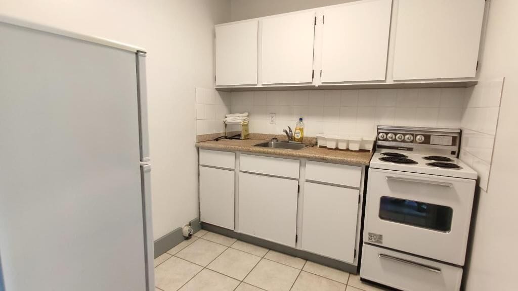 A compact kitchen with white cabinets, a double oven, and a sink.