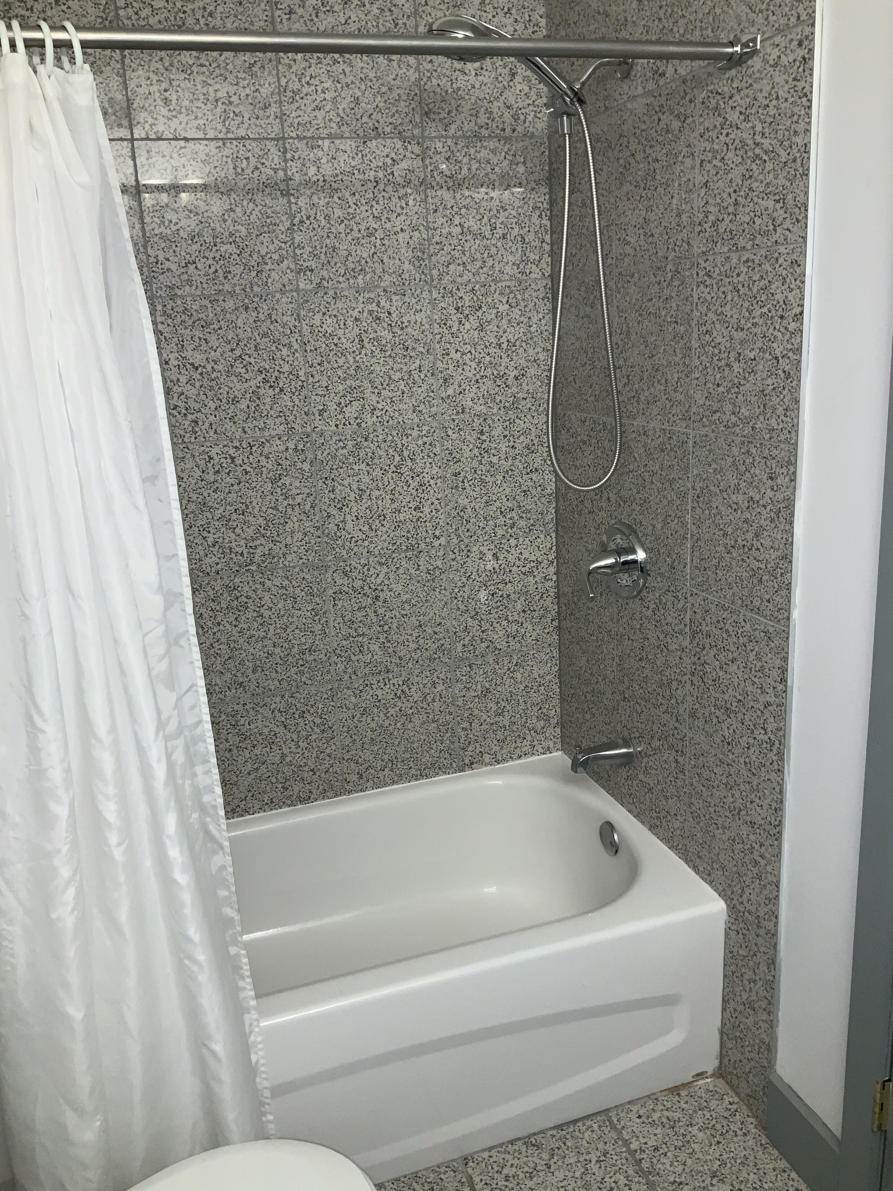 Un baño moderno con una bañera independiente, un cabezal de ducha y una mampara de vidrio.