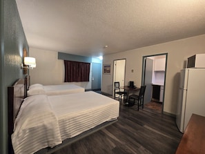 Une chambre d’hôtel avec deux lits, un bureau avec une chaise, un réfrigérateur et un four à micro-ondes.