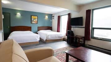 A hotel room with two beds, a television, a desk, and a window with curtains.