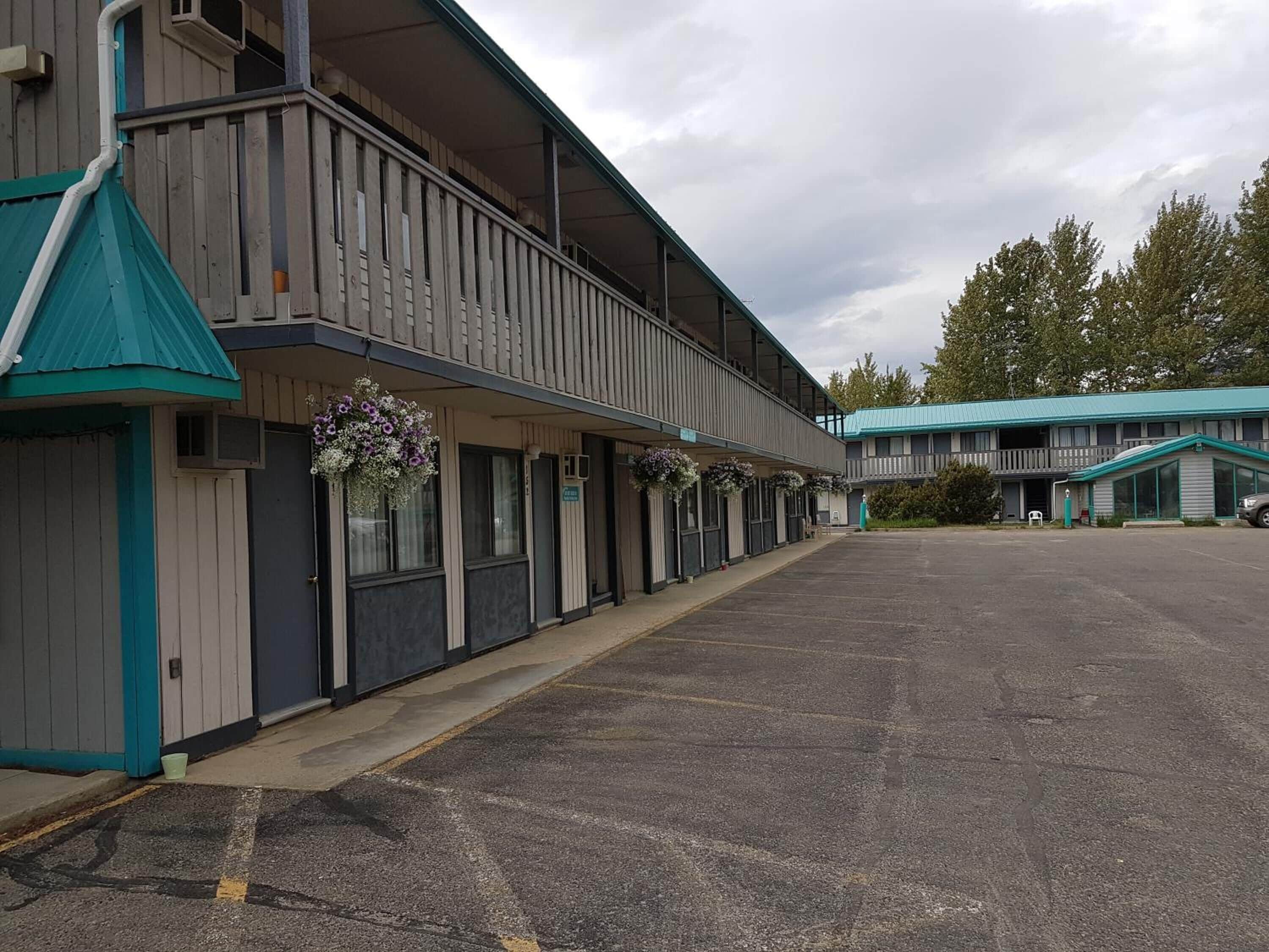 Un motel con estacionamiento techado y una hilera de habitaciones con balcones.
