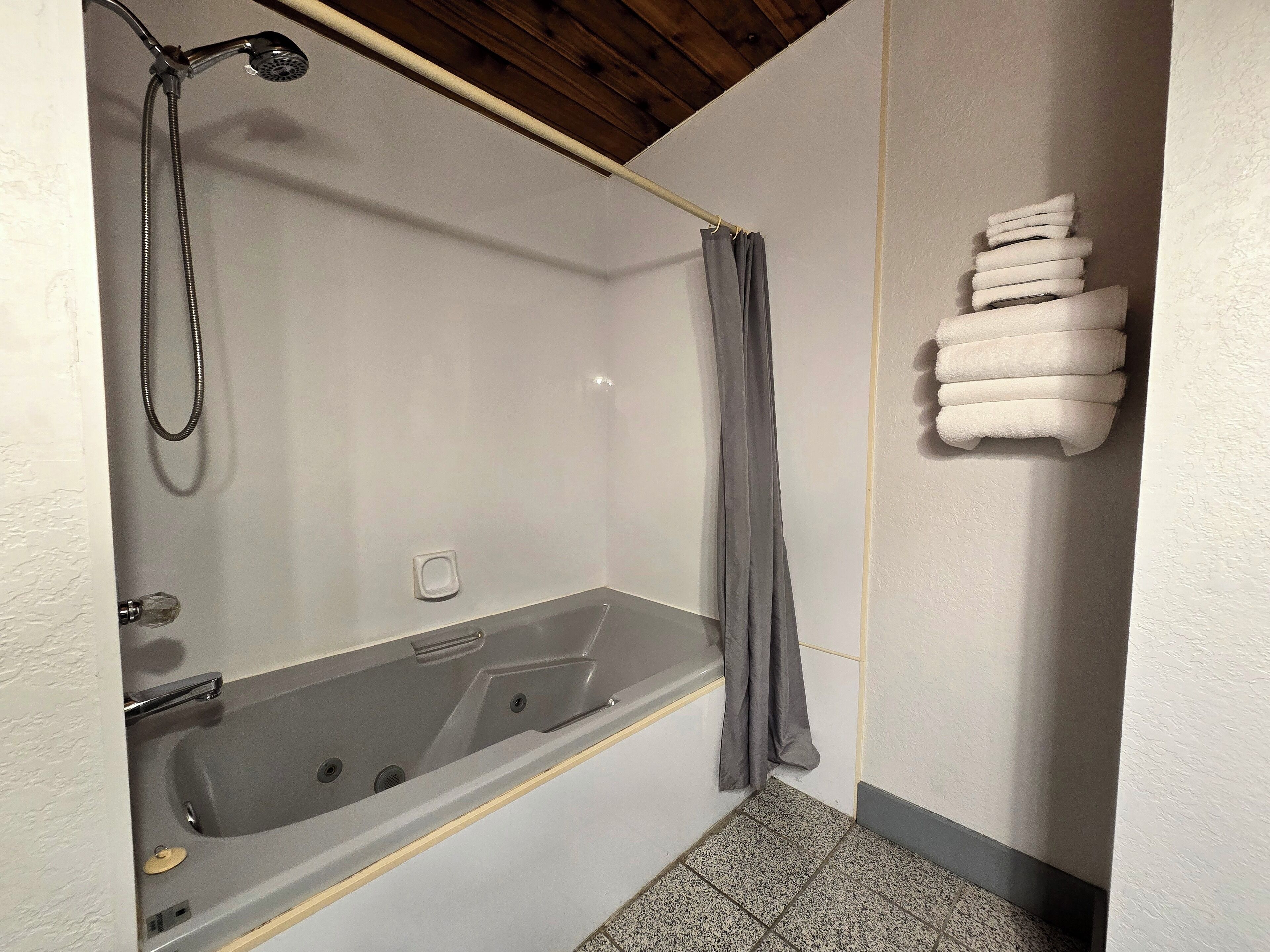 A bathroom with a bathtub, shower, and a towel rack with towels.