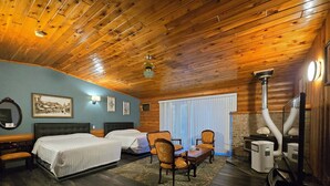 A room with two beds, a wooden ceiling, a fireplace, and a dining area. - Alpine Inn (Valemount)