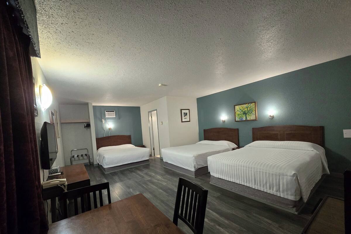 A hotel room with two beds, a desk, and a chair.