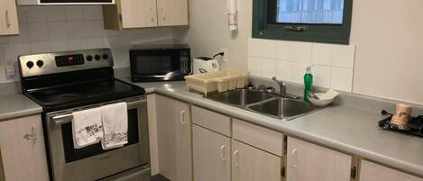 Una cocina con electrodomésticos de acero inoxidable, un lavamanos doble y armarios de color claro.