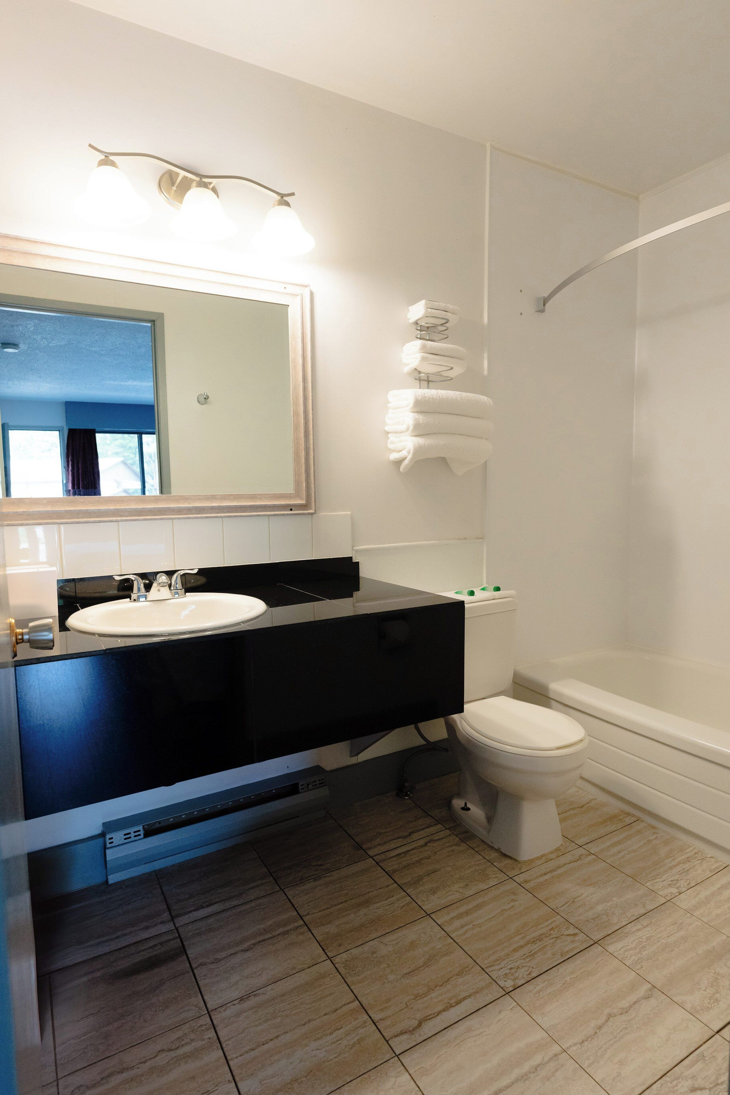Une salle de bain moderne avec un grand miroir, deux lavabos, des toilettes et une douche.