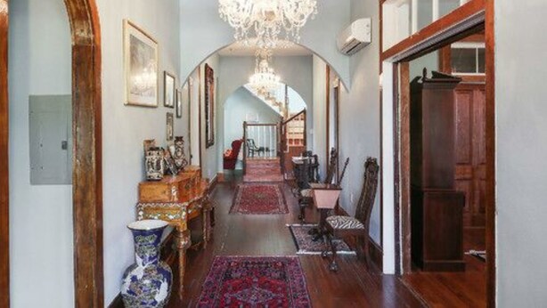A hallway with a chandelier, wooden flooring, and a red carpet. - Oakview Bed and Breakfast (New Orleans)