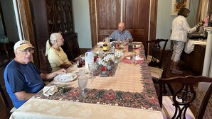 A dining table set with various dishes and drinks, surrounded by wooden chairs. - Oakview Bed and Breakfast (New Orleans)
