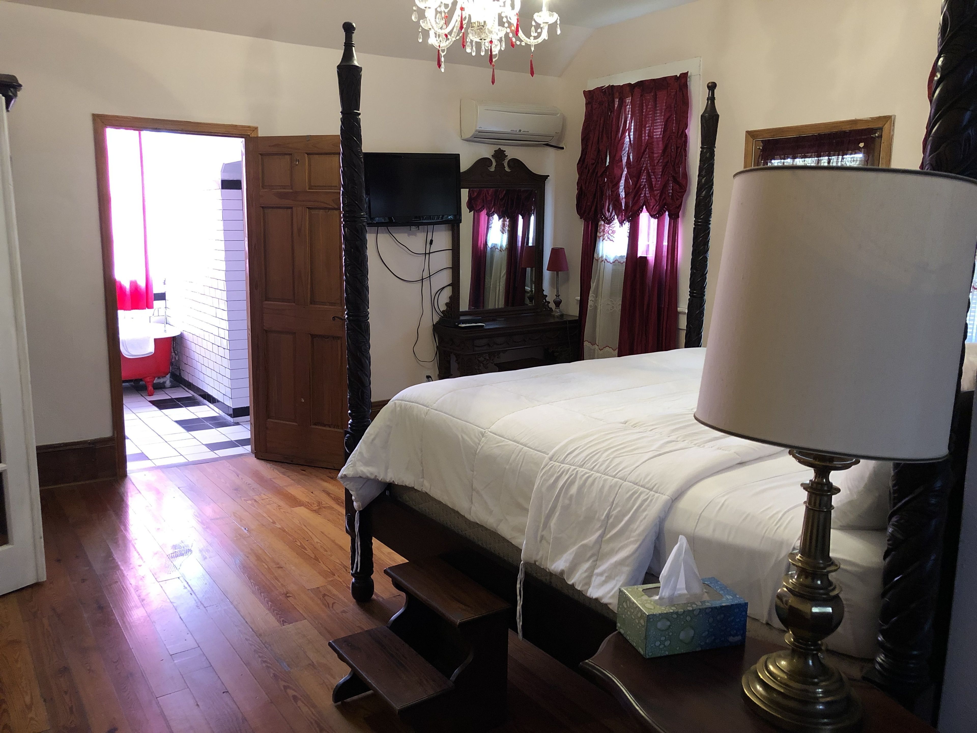 Une chambre à coucher avec un lit à baldaquin, une lampe de chevet, un miroir et une commode en bois.