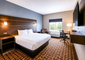 A hotel room with a bed, bedside tables, a desk, a chair, a TV, and a window.