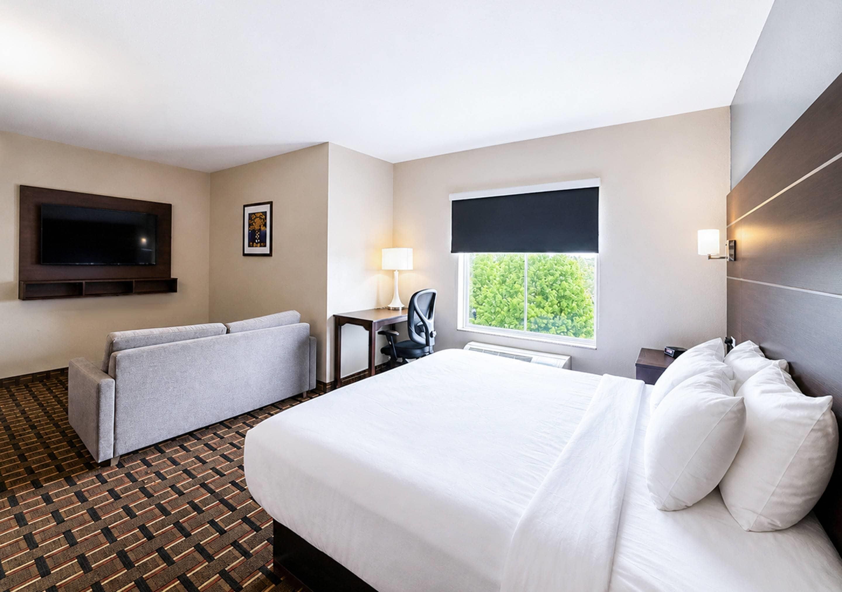 Ein Hotelzimmer mit Bett, Sofa, Schreibtisch, Fernseher und einem Fenster mit Blick.