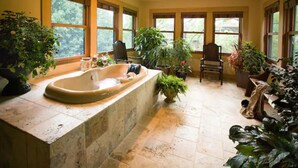 A spacious bathroom with a freestanding bathtub, multiple windows, and various potted plants. - 1900 Inn on Montford (Asheville)