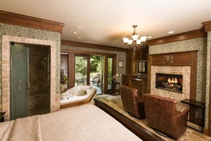 A spacious bedroom with a large bed, a fireplace, a jacuzzi, and a view of the outdoors. - 1900 Inn on Montford (Asheville)