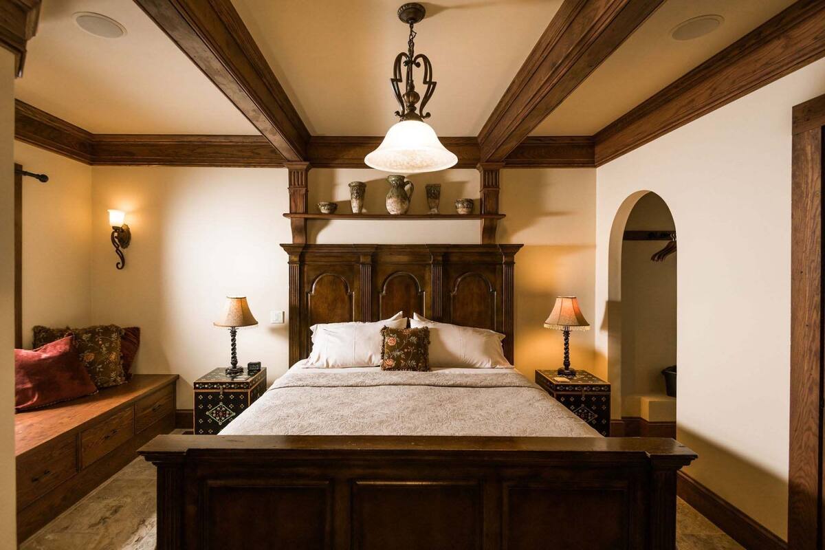 Un dormitorio con una cama de madera, dos mesitas de noche, una araña y una estantería decorativa sobre la cama.