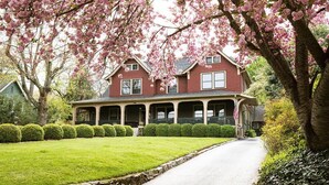 A two-story house with a porch, surrounded by well-maintained lawns and trees. - 1900 Inn on Montford (Asheville)