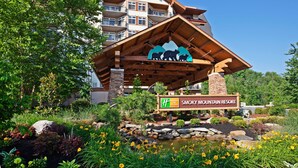 Un edificio de resort con fachada de madera, un cartel que indica que es Smoky Mountain Resort, y el logotipo de Holiday Inn Express Club.