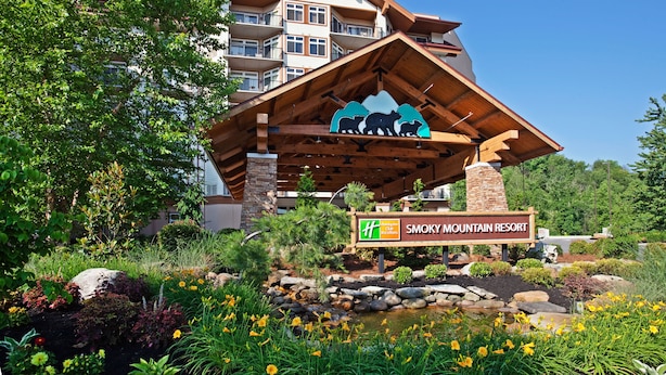 A resort building with a wooden facade, a sign indicating it is Smoky Mountain Resort, and a logo for Holiday Inn Express Club.