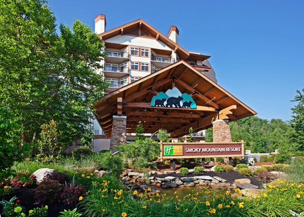 Un edificio de resort con fachada de madera, un cartel que indica que es Smoky Mountain Resort, y el logotipo de Holiday Inn Express Club.