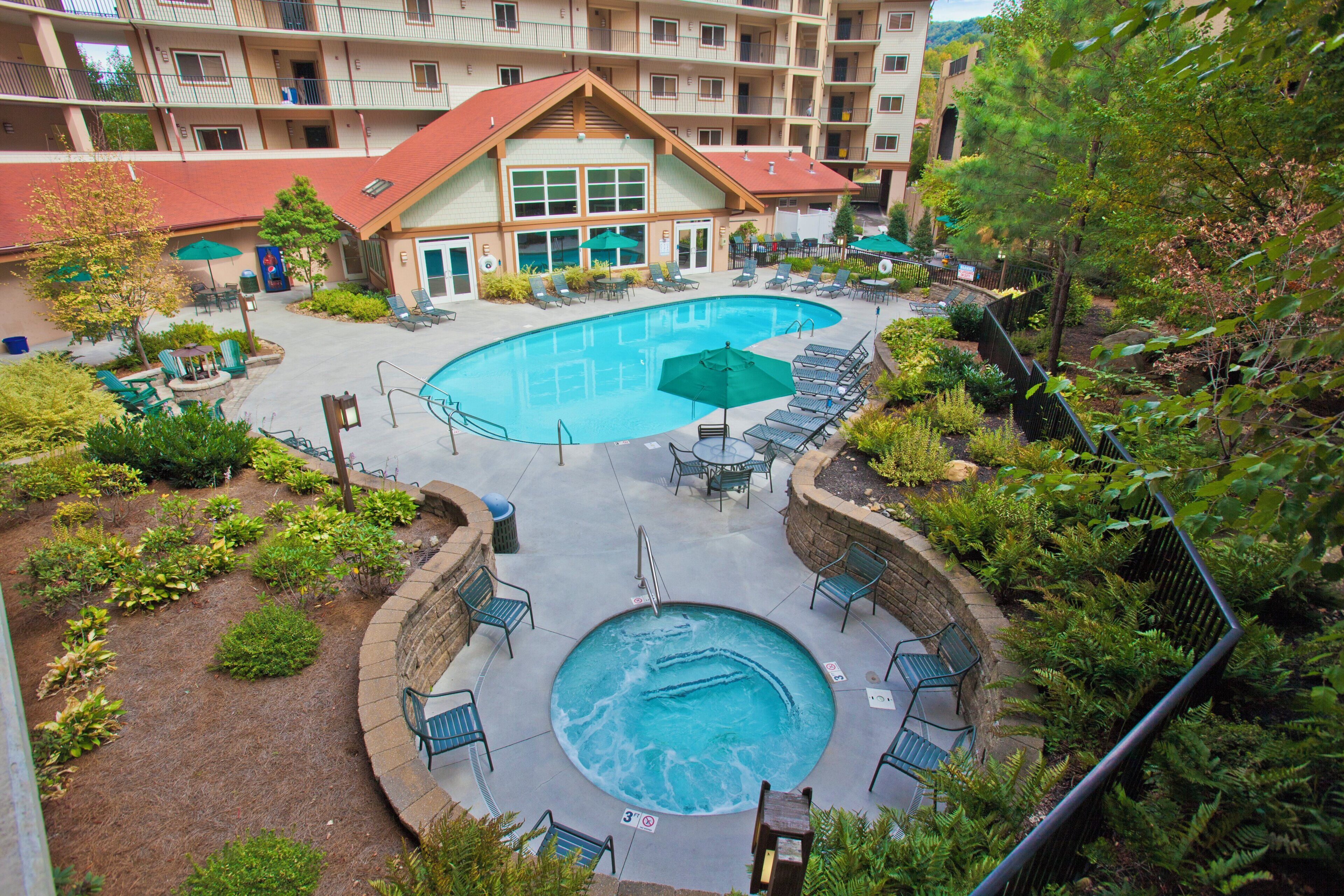 A hotel with a swimming pool, lounge chairs, and a landscaped garden.